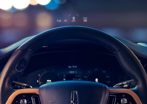 The available head-up display projects data on the windshield above the steering wheel inside a 2022 Lincoln Corsair as the driver navigates the city at night | Fair Oaks Lincoln in Naperville IL