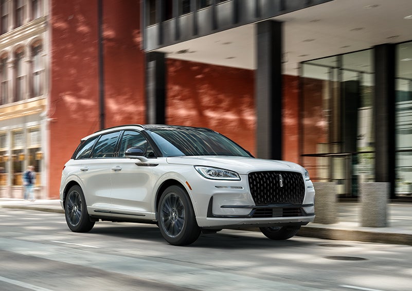The 2024 Lincoln Corsair® SUV with the Jet Appearance Package and a Pristine White exterior is parked on a city street. | Fair Oaks Lincoln in Naperville IL
