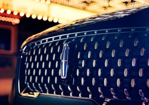 The Corsair Grand Touring grille shows floating chrome ovals that catch the glowing light of a theater marquee and frame the distinctive Lincoln Star | Fair Oaks Lincoln in Naperville IL