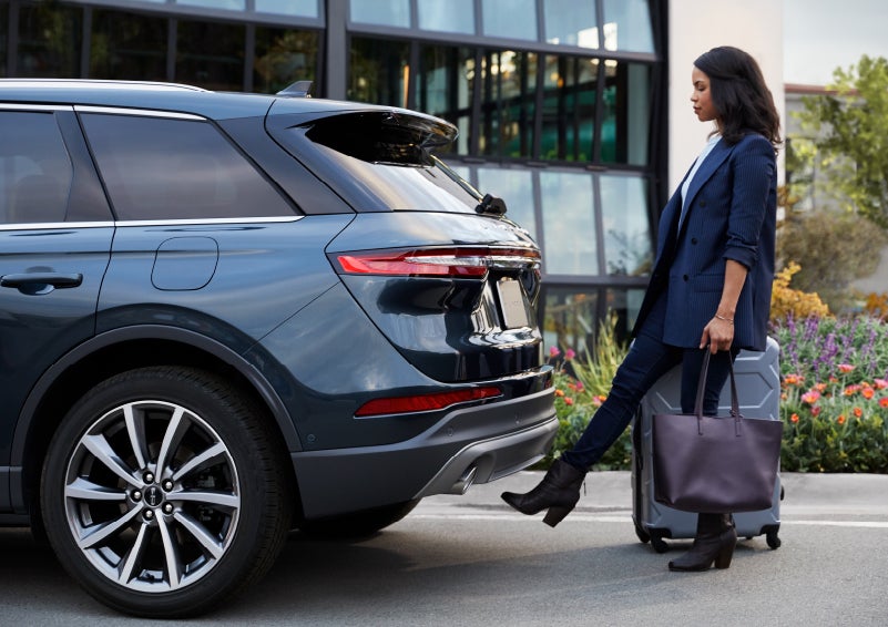 A woman with luggage and a bag opens the available hands-free liftgate by kicking her foot under the bumper | Fair Oaks Lincoln in Naperville IL