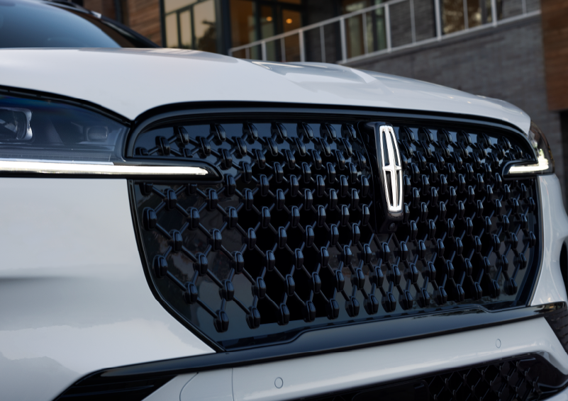 The black grille of a white 2025 Lincoln Aviator® SUV is shown with its fog lights on. | Fair Oaks Lincoln in Naperville IL