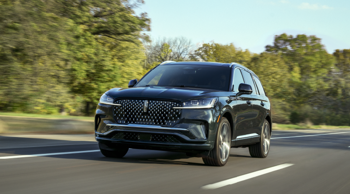 A 2025 Lincoln Black Label Aviator® SUV is being driven down a road lined with trees. | Fair Oaks Lincoln in Naperville IL