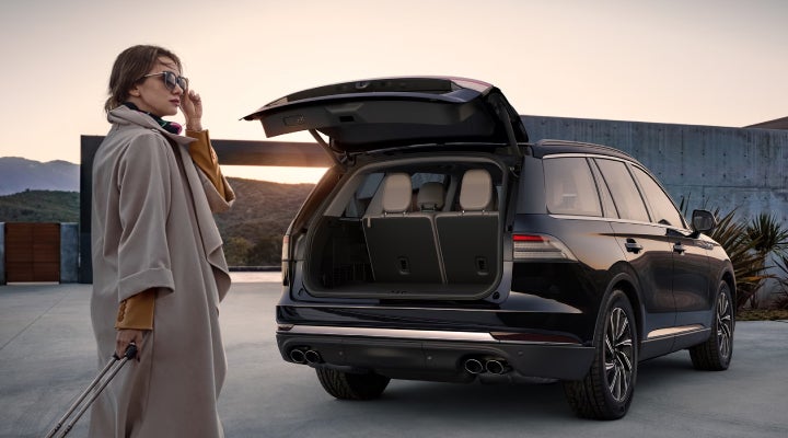 A woman approaches a 2026 Lincoln Aviator® SUV with its rear liftgate open. | Fair Oaks Lincoln in Naperville IL
