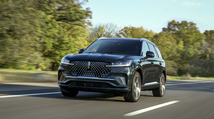 A 2026 Lincoln Black Label™ Aviator® SUV is being driven down a road lined with trees. | Fair Oaks Lincoln in Naperville IL