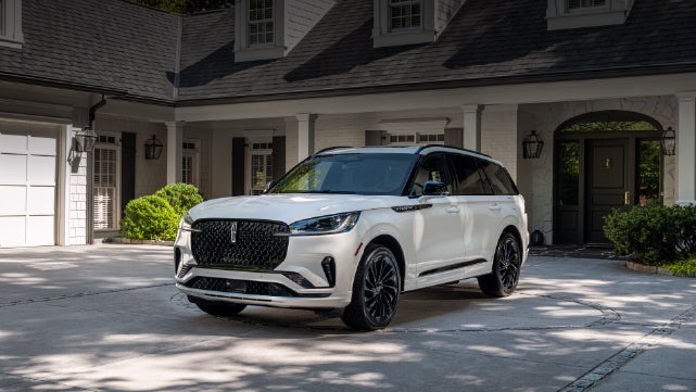 A white 2026 Lincoln Aviator® SUV is parked in the driveway of a luxury home. | Fair Oaks Lincoln in Naperville IL