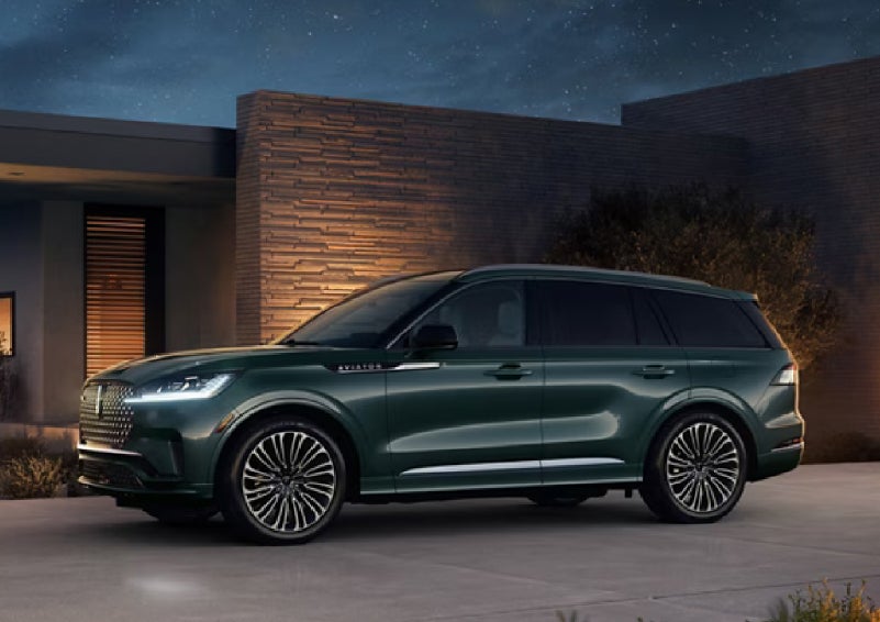 A green 2027 Lincoln Aviator® SUV is parked outside a contemporary home. | Fair Oaks Lincoln in Naperville IL