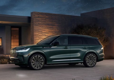 A green 2027 Lincoln Aviator® SUV is parked outside a contemporary home. | Fair Oaks Lincoln in Naperville IL