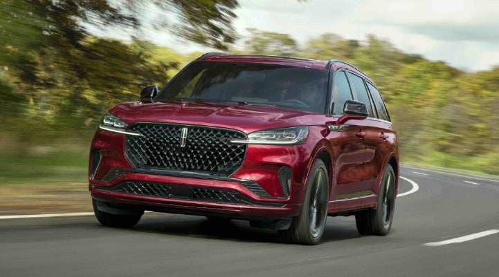 A 2027 Lincoln Aviator® SUV is being driven on a country road | Fair Oaks Lincoln in Naperville IL