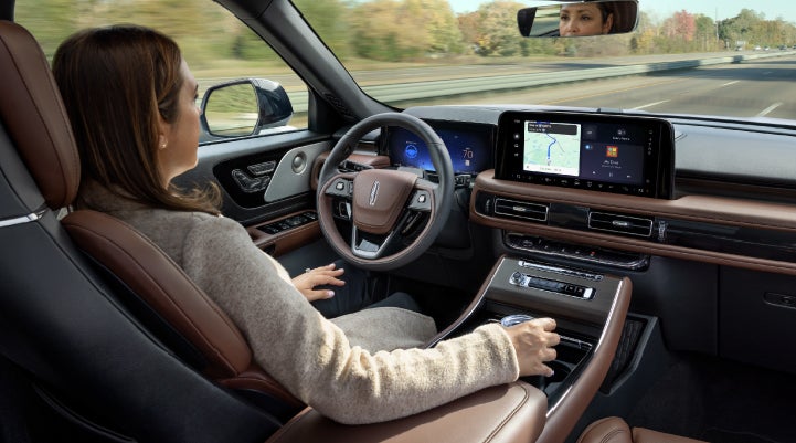 A 2027 Lincoln Aviator® SUV is being driven hands-free on a highway lined with trees. | Fair Oaks Lincoln in Naperville IL