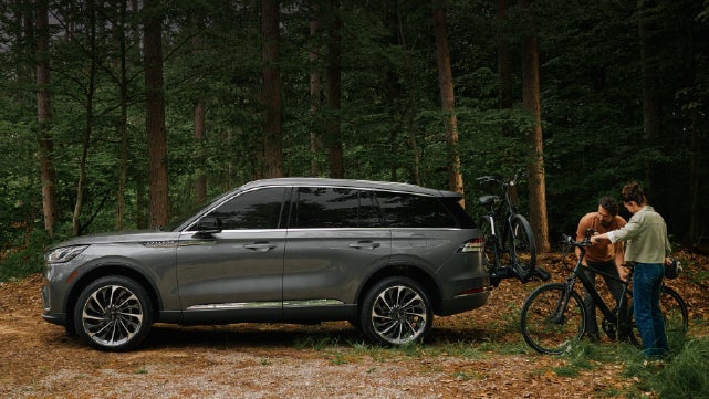A father and son load e-bikes on a bike rack attached to a 2027 Lincoln Aviator® SUV. | Fair Oaks Lincoln in Naperville IL