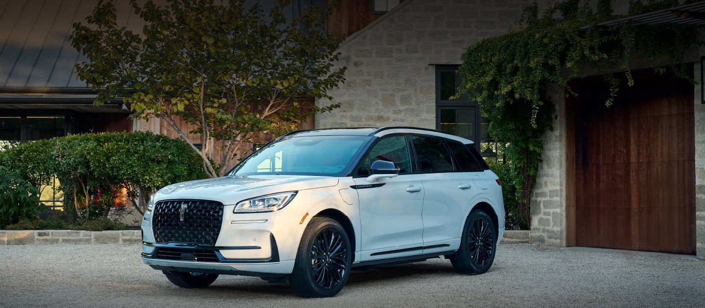 A 2025 Lincoln Corsair® SUV is parked in front of a stately home.
